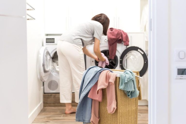 woman moving laundry from washer to dryer